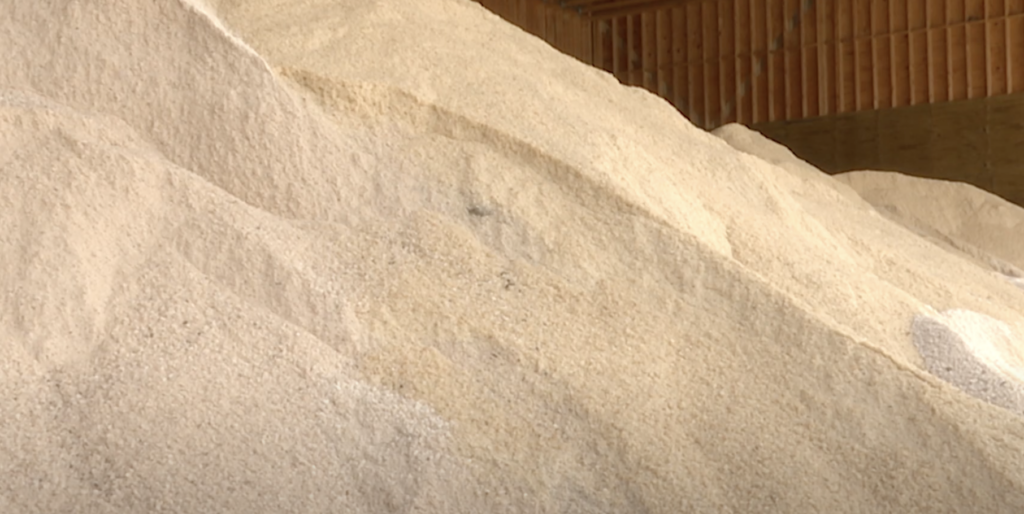 A tan and white colored pile of rock salt in a salt bay.